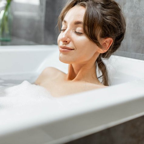 Frau entspannt in Badewanne.