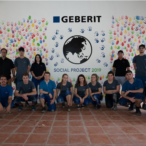 Die Auszubildenden und Teilnehmer des Sozialprojekts von Geberit vor der gestalteten Schulwand in Kambodscha.
