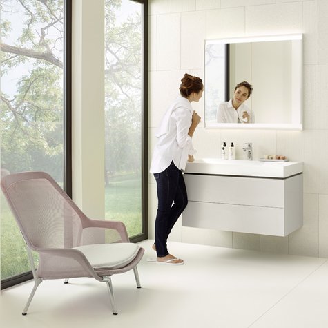 Frau in modernem Badezimmer vor Geberit Lichtspiegelschrank mit ComfortLight