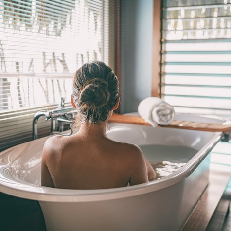Wellness zuhause: Frau entspannt in Badewanne mit Fensterblick