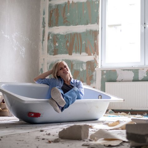Frau sitzt in Baustelle im Bad.