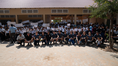 Die Teilnehmer des Sozialprojekts von Geberit und die Schüler aus Siem Reap haben sich mit Plakaten vor der Schule aufgestellt.