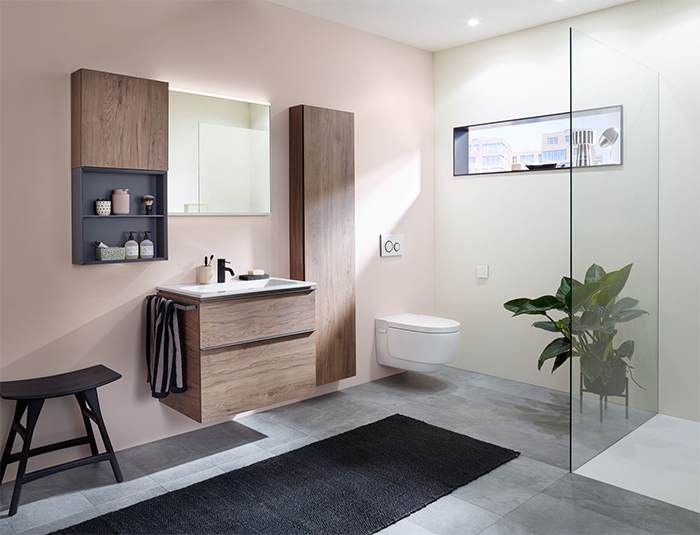 Tag: Badezimmer der Serie Geberit iCon mit Holzmöbeln, Hocker, WC, Pflanze und begehbarer Dusche.