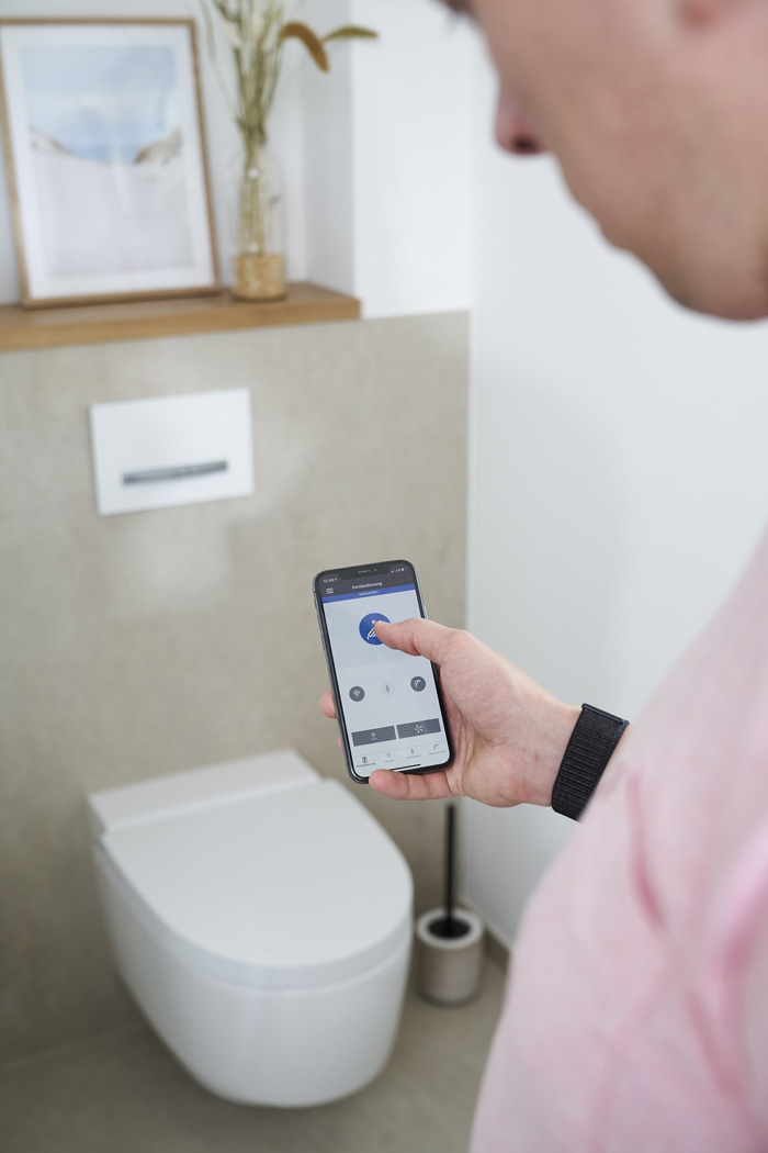 Mann steuert das Geberit AquaClean Dusch-WC per App am Smartphone