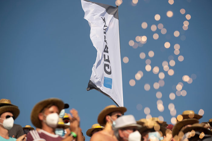 Beachvolleyball-Fans mit Hüten vor einer Geberit-Flagge